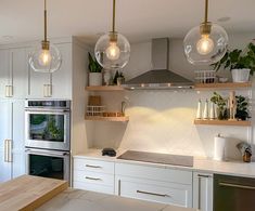 A kitchen with a grey induction cooktop, white cabinets, white tile, and brass pendant lights. Induction Oven Kitchen, Induction Kitchen Design, Kitchen Cooktop Alcove, Induction Stove Kitchens, Kitchen With Electric Cooktop, Induction Cooktop Kitchen Design, Kitchen With Induction Cooktop, Kitchen With Cooktop, Induction Cooktop Kitchen