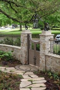 an iron gate and stone walkway leading to a park