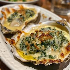 three oysters with cheese and spinach on a white plate, ready to be eaten