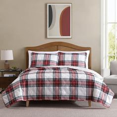 a bed in a room with a plaid comforter and pillows