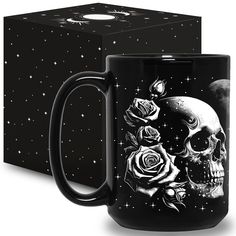 a black coffee mug with a skull and roses on it next to a gift box