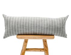 a wooden stool with a gray and white pillow on it