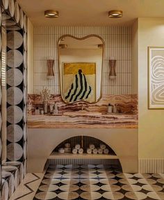 a bathroom with a black and white checkerboard floor, gold framed mirror over the sink