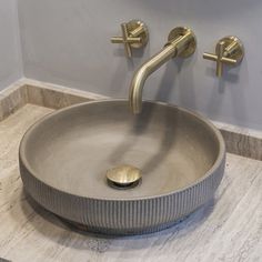 a bathroom sink with two brass faucets on the wall and marble counter top