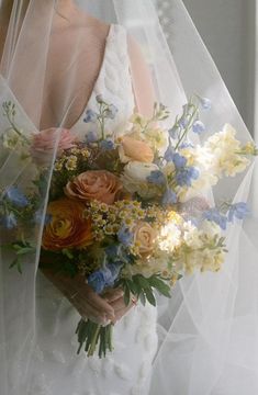 a woman wearing a veil holding a bouquet of flowers