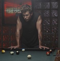 a man leaning over a pool table with balls in front of him