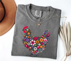 Floral Chicken Comfort Colors Shirt, Unisex Hen Shirt, Retro Adult Farm  Chicken Lover Shirt, Women's Chicken Gift Comfort Colors introduces its garment-dyed t-shirt; a fully customizable tee made 100% with ring-spun cotton. The soft-washed, garment-dyed fabric brings extra coziness to your wardrobe while the relaxed fit makes it an excellent daily choice. The double-needle stitching throughout the tee makes it highly durable while the lack of side-seams helps the shirt retain its tubular shape. Chicken Lady Shirt, Floral Chicken, Farm Chicken, Chicken Lover Gifts, Chicken Gifts, Chicken Shirts, Chicken Lady, Chicken Lovers, Comfort Colors Shirt