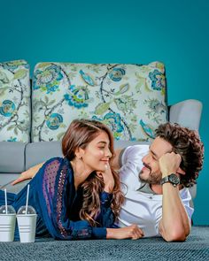 a man and woman laying on the floor in front of a couch with two buckets