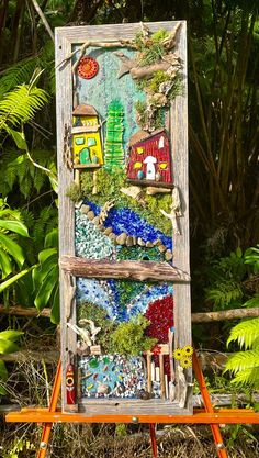 an easel with a painting on it in front of some plants and trees,