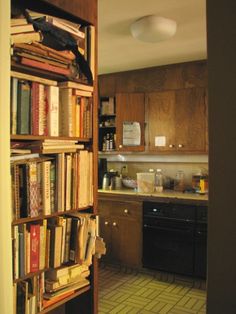 an open book shelf filled with lots of books in a kitchen next to a stove top oven