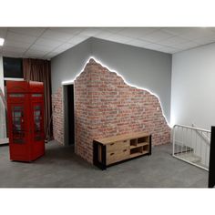 a red phone booth sitting next to a brick wall in an empty room with white railings