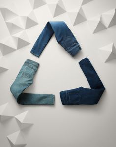 three pairs of blue jeans laying on top of each other in the shape of a triangle