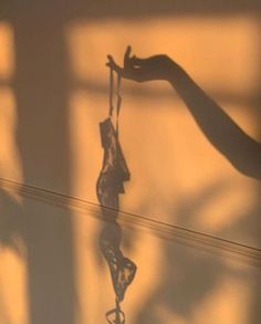 the shadow of a person's hand holding an object in front of a wall