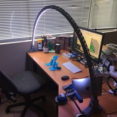 a desk with a computer monitor, keyboard and other office supplies on top of it