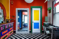 a brightly colored room with checkered flooring and colorful walls, including an open door