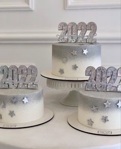 three tiered cake with silver stars and numbers on it's sides, sitting on top of a white table