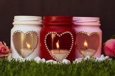 three mason jars with candles in the shape of hearts on top of green grass next to pink roses