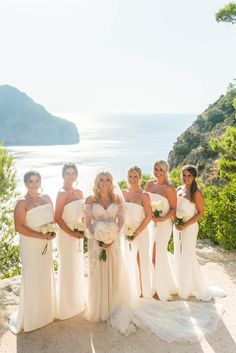 a group of women standing next to each other on top of a hill near the ocean