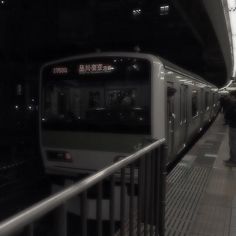 a subway train pulling into the station with people waiting for it to stop at night