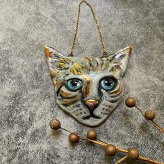 a ceramic cat with blue eyes hanging from a chain