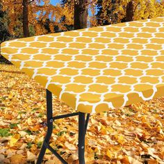 an ironing board covered in yellow and white circles sits on top of some leaves