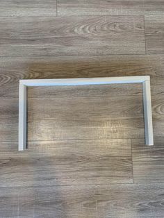 a wooden floor with a white frame on the bottom and an empty shelf below it