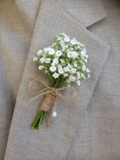 a boutonniere with baby's breath flowers tied to the lapel