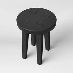 a small black stool with four legs and an open top on the side, sitting in front of a white background