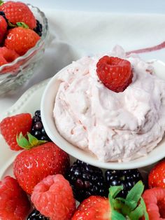 a bowl of whipped cream surrounded by berries