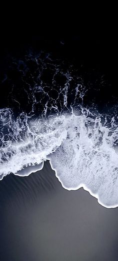 an aerial view of the ocean with waves coming in from the shore and dark background