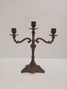 an old metal candelabra with three candles on it's stand, against a white background