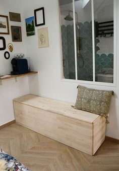 a wooden bench sitting next to a window in a room with pictures on the wall