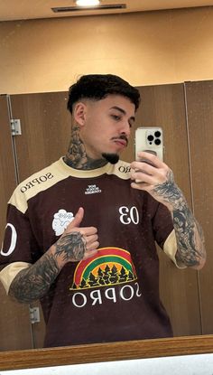 a man taking a selfie in front of a mirror with tattoos on his arms