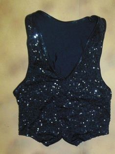 a black top with sequins on it is laying on the floor next to a wall