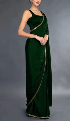 a woman in a green dress with gold trims on the waist and shoulder, posing for