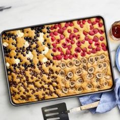 an american flag cake with berries, bananas and blueberries on it next to a spatula