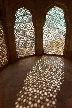 an intricately designed room with two windows and shadows on the wall, in india