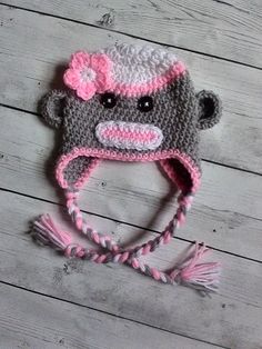 a crocheted hat with a pink flower on the side and a monkey face