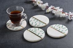 four white cookies with green sprinkles next to a cup of tea and flowers