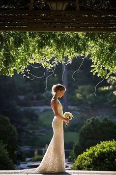 a woman in a wedding dress standing under a tree