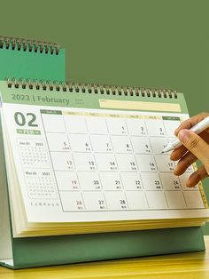 a person writing on a calendar with a pen