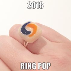 a hand holding a ring with an orange, blue and white design on it