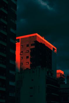 a tall building with red lights on it's side and dark clouds in the background