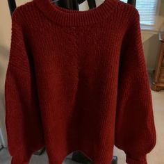 a red sweater hanging on a rack in a room