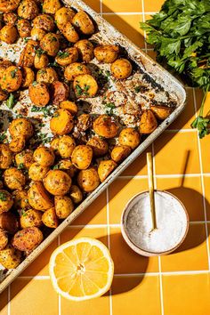 a tray filled with baked potatoes next to a lemon slice and parsley on the side