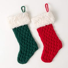 two knitted christmas stockings with green and red stocking hanging from the top, on a white background