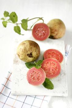 three pieces of fruit sitting on top of a white plate next to a green leaf