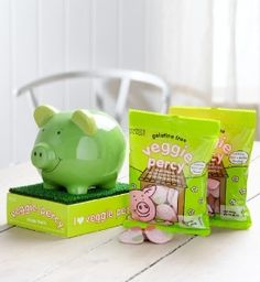 a piggy bank sitting on top of a table next to two bags of chips