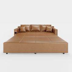 a tan leather couch with pillows on it's back end and footrests