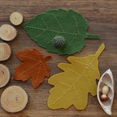 felt leaves and acorns are arranged on a wooden surface